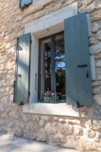 Volets battants vert gris sur une maison en pierre